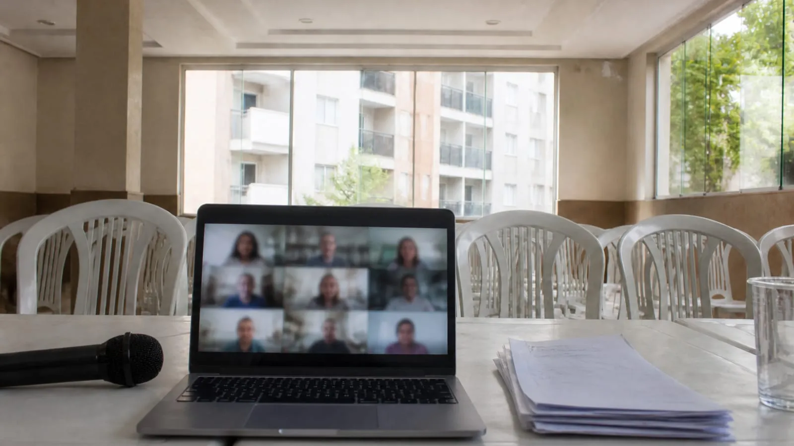 Notebook em chamada de vídeo desfocada sobre a mesa de uma sala de assembleia